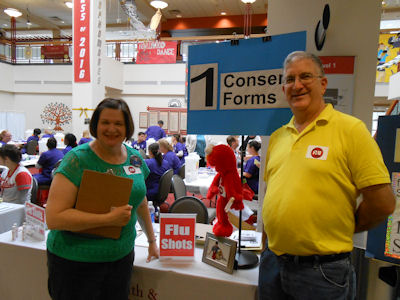 Elaine and Ron Plotkin are standing in front of the check-in table at the SHAC Flu Shot Clinic.
