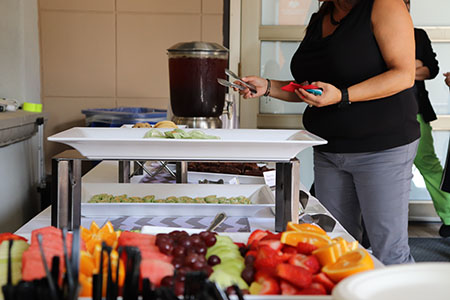 A young woman serves herself at the food and refreshments table.
