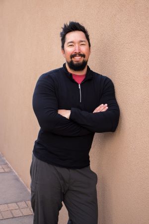 Benjamin Ferguson smiles and leans against an adobe wall.