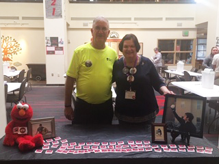 Ron and Elaine Plotkin stand behind the Flu Shot check-in table.