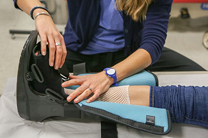 Close-up of a nurse putting on an orthopedic boot on a patient's foot injury.
