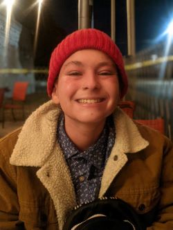 Grace Conlin wears a hat and coat and smiles for the camera.