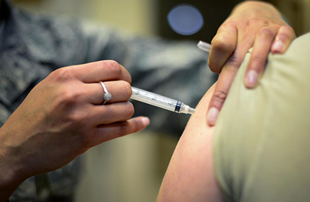 A nurse injects a patient's upper arm.