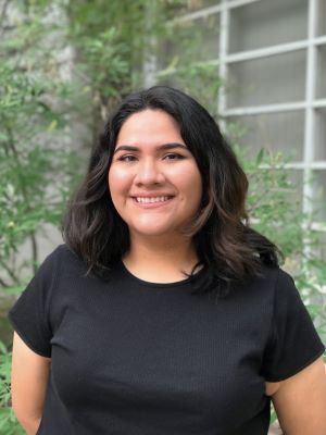 Lizbeth Olivarez is standing outdoors and smiling for the camera.