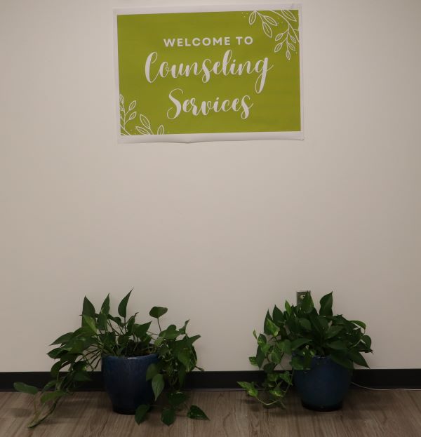 Counseling Services sign is posted in the hallway with plants underneath it.
