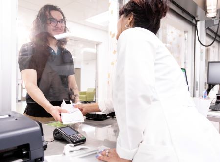 SHAC Pharmacist hands a prescription to a patient.