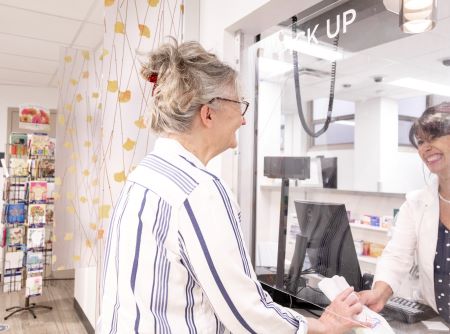 SHAC Pharmacist hands a prescription to a staff member.