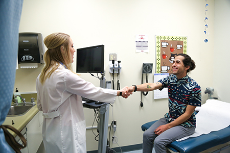 A SHAC medical provider greets a patient in an exam room.