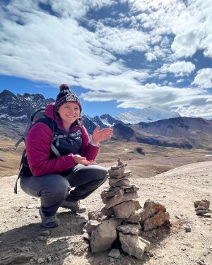 Tiffany Martinez-Durant poses on a mountain top next to a rock sculpture she created in Peru.