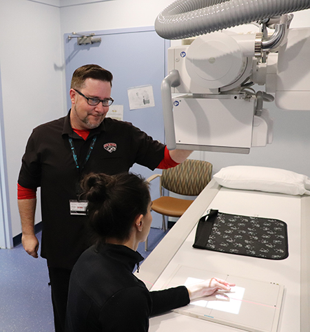 An X-Ray technician prepares to X-ray a patient's hand.